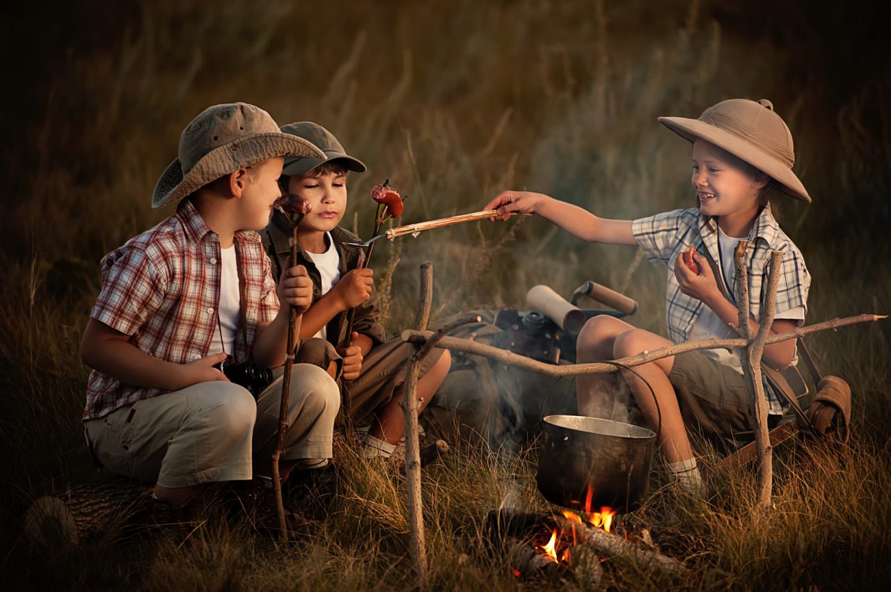 Group of children sitting around the campfire travelers