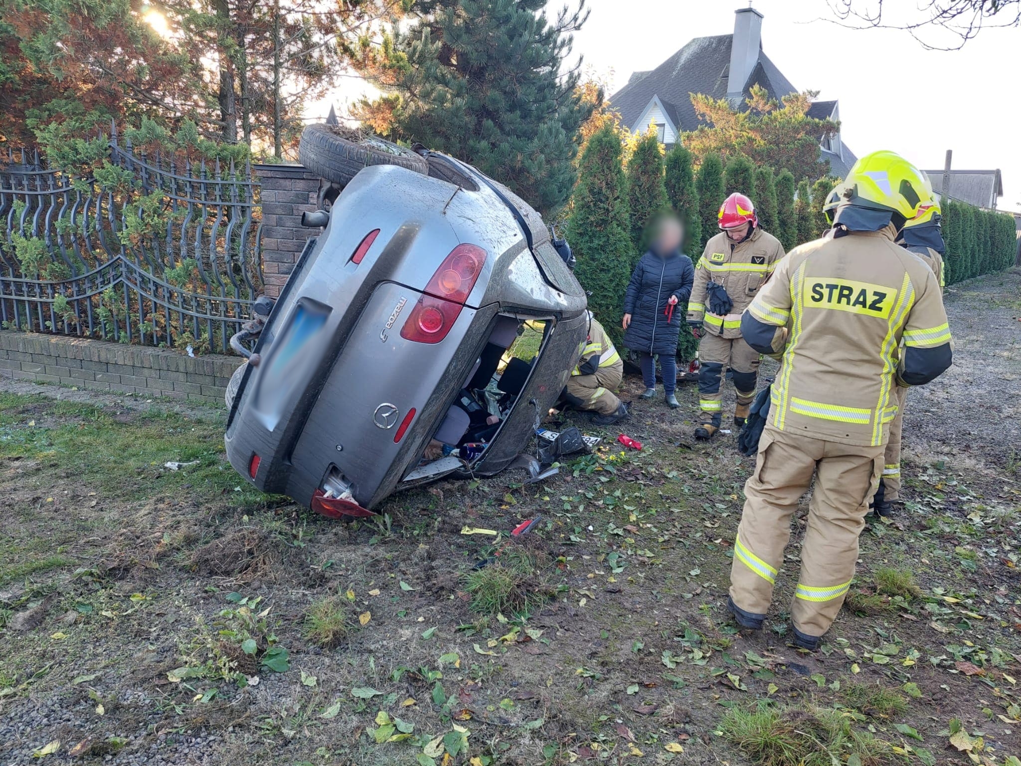 Mazda wypadła z drogi, dachowała i uderzyła w ogrodzenie. Kierująca trafiła do szpitala (zdjęcia)