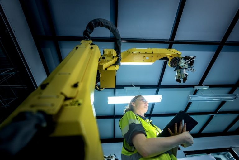 Pracownica firmy relokacyjnej kalibruje robota przemysłowego